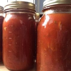 three jars filled with red liquid sitting on top of a table