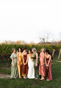 a group of women standing next to each other on top of a grass covered field