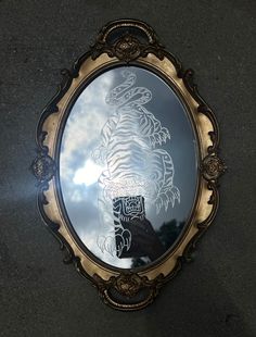 a mirror with a reflection of a tiger on it's face and clouds in the background