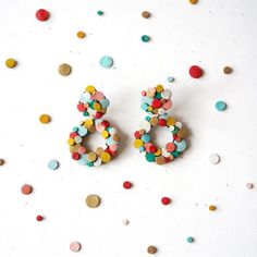 two pairs of colorful earrings sitting on top of confetti