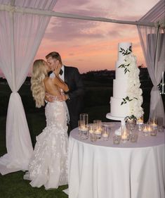 a bride and groom kissing in front of a wedding cake with candles on the table