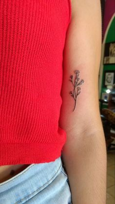 a woman's arm with a small flower tattoo on the back of her left arm