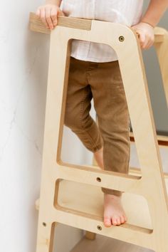 a young child standing on top of a wooden ladder