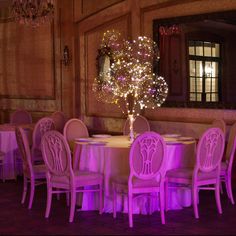 a round table with pink chairs and lights in the center is set up for a formal function