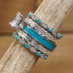 a stack of rings sitting on top of a piece of wood with turquoise stones in it