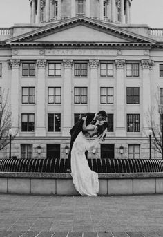 a bride and groom kiss in front of the state capitol building on their wedding day