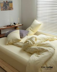 an unmade bed in a bedroom with white sheets and pillows on top of it