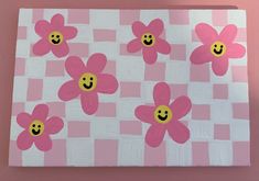 a pink and white checkered table cloth with flowers painted on the top, smiling faces in the middle