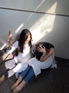 two women sitting next to each other on the ground