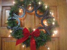 a wreath made out of horseshoes and christmas lights on a door with a red bow