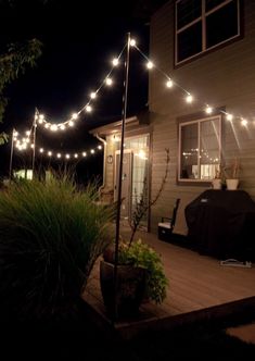 an outdoor patio with string lights strung over the deck and in front of a house