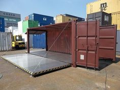 a large cargo container sitting in the middle of a parking lot next to shipping containers