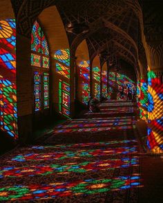 colorful stained glass windows in the middle of a building with people walking around them and shadows on the floor