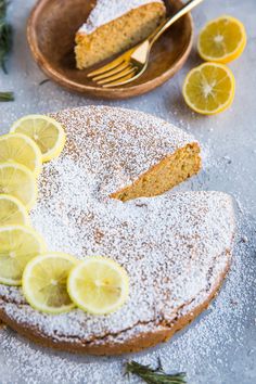 lemon cake with powdered sugar and sliced lemons on the plate next to it