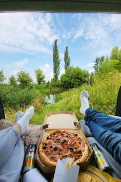 a pizza sitting on top of a cardboard box next to a person's feet