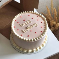 a birthday cake sitting on top of a table next to a box with the words happy birthday written on it