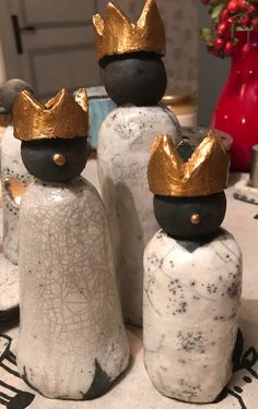 three decorative salt and pepper shakers with gold crowns on their heads sitting on a table