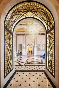 an ornate entry way with chandelier in the middle and marble flooring on both sides