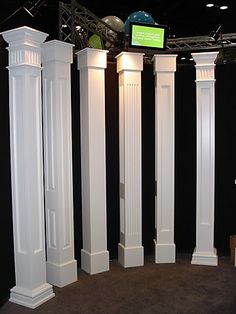 four white pillars are standing in the middle of a room with black walls and carpet