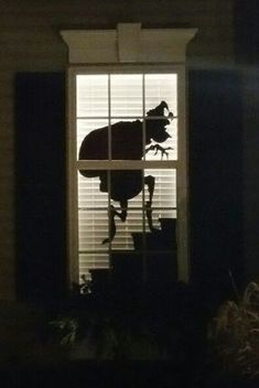 a silhouette of a cow standing on top of a window sill in the dark