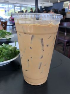 a drink sitting on top of a table next to a plate of salad and other food