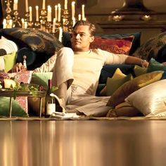 a man sitting on top of a couch surrounded by pillows and candles in a living room