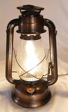 an old fashioned lantern is lit up on a white sheet