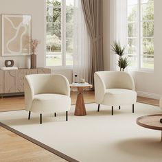 two white chairs sitting on top of a rug in a living room next to a coffee table