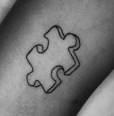 a black and white photo of a person's arm with a puzzle piece tattoo on it