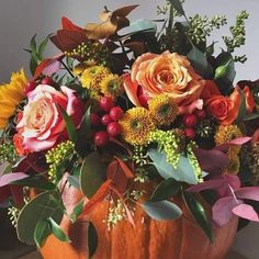 a pumpkin filled with lots of flowers on top of a table