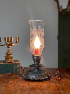 a candle is lit on a table next to an old book and two candlesticks