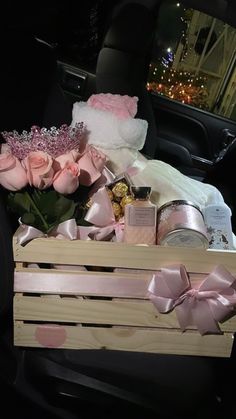 a wooden crate filled with pink roses and other items in the back of a car