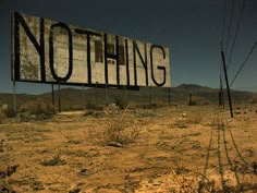 there is a sign that says nothing in the middle of the desert with mountains in the background