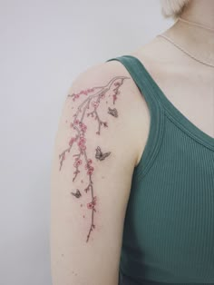 a woman's arm with pink flowers and butterflies tattooed on her left upper arm