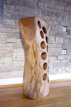 a wooden object sitting on top of a hard wood floor next to a brick wall