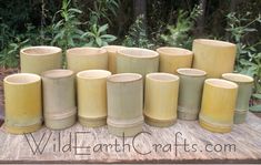 a group of yellow vases sitting on top of a wooden table in front of trees