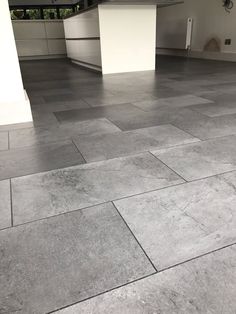 an empty kitchen with grey tile flooring and white counter tops in the middle of it