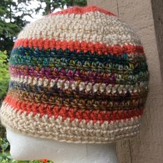 a white mannequin head wearing a multicolored knitted beanie hat