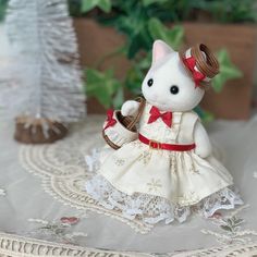 a small white cat figurine with a red bow on it's head