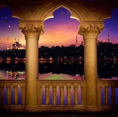 the view from an outside balcony at night with lights in the sky and water reflecting on the ground