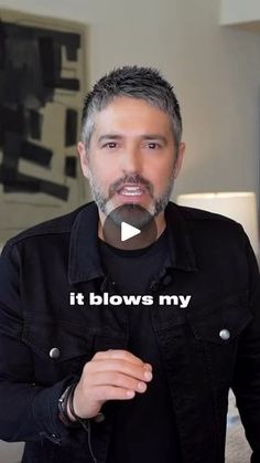 a man with grey hair and beard wearing a black shirt is standing in front of a mirror