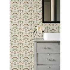 a white sink sitting under a mirror next to a wall paper with flowers on it