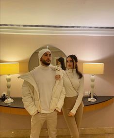 a man and woman standing in front of a mirror wearing white clothes with hoods on