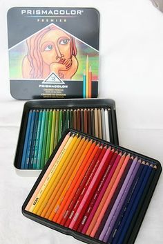 there are many colored pencils in the box next to each other on the bed