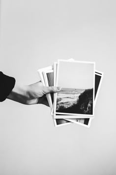 a hand holding four black and white photographs