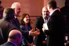 two men and one woman are shaking hands with each other at a business meeting or social gathering