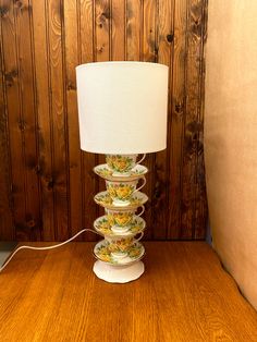 a lamp that is sitting on top of a wooden table in front of a wood paneled wall