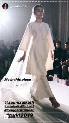 a woman is walking down the runway wearing a white outfit