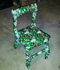 a green and white chair sitting on top of a floor next to a cardboard box