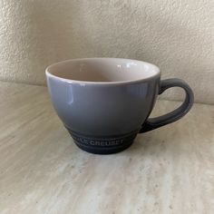 a gray and white coffee cup sitting on top of a table